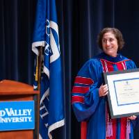Recipient stands next to President holding her award on stage